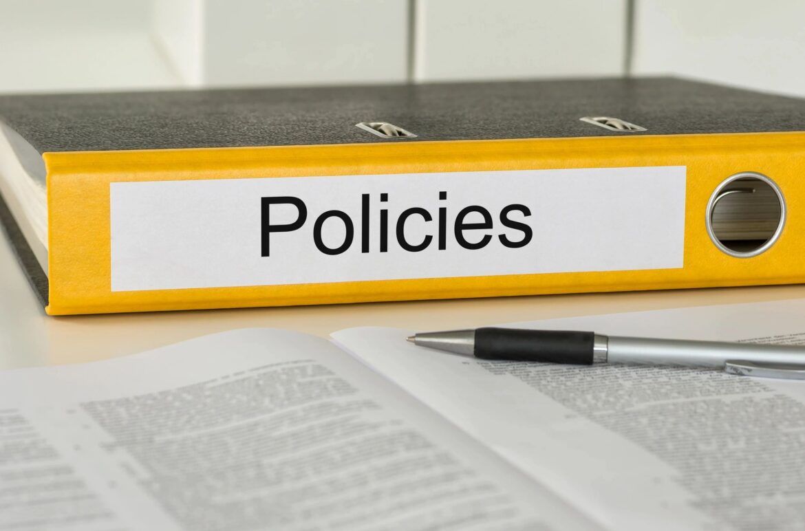 Policies binder and pen on a desk, symbolizing automated regulatory compliance and reporting