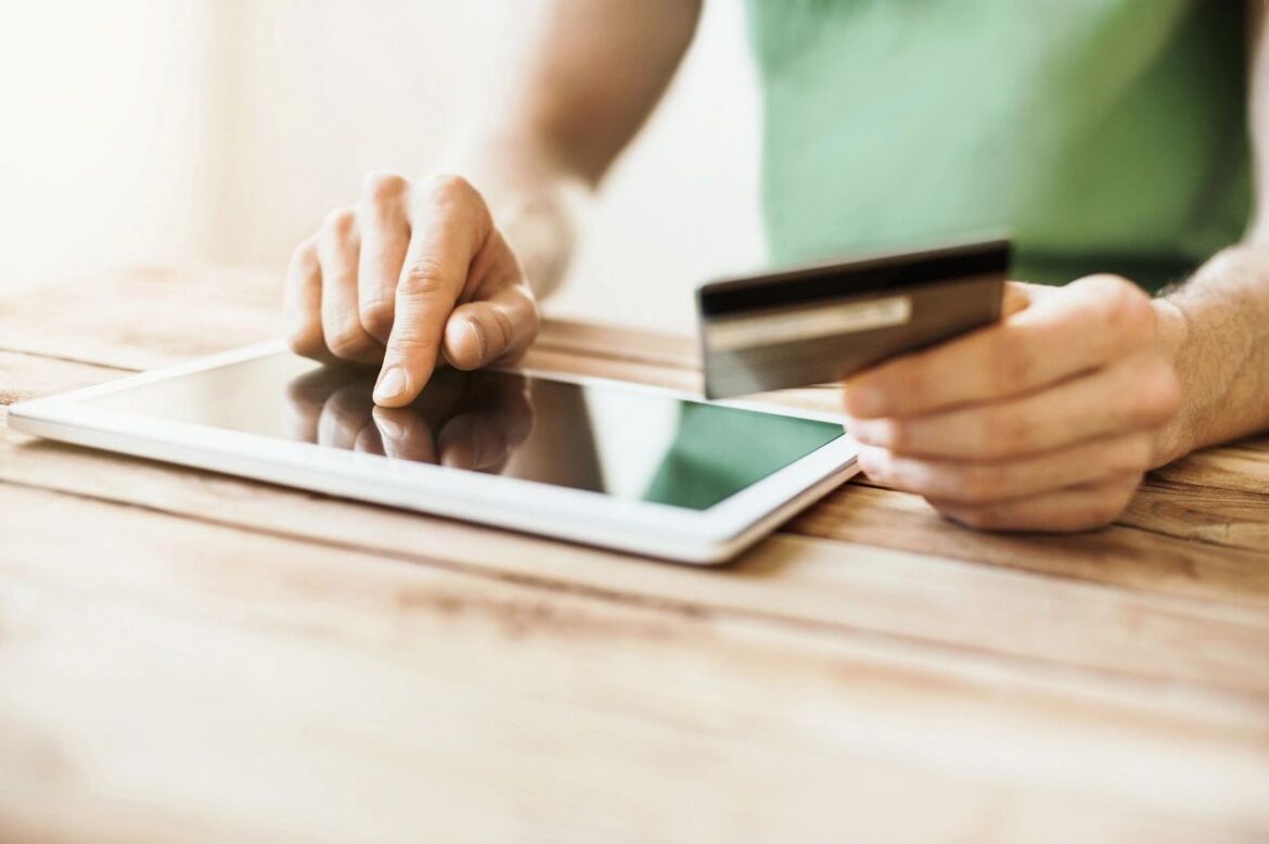 Hand making a mobile payment with a credit card on a tablet, representing embedded finance